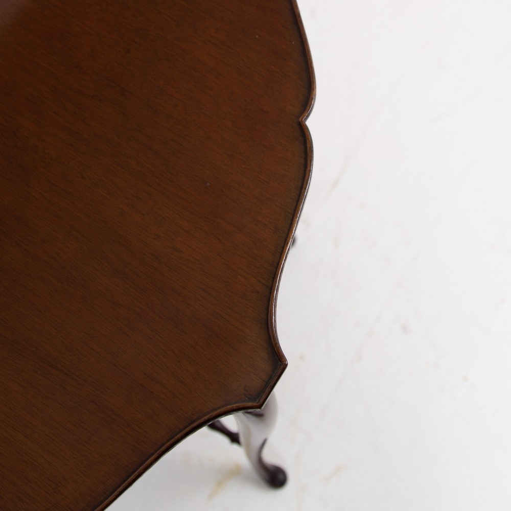 An Edwardian mahogany occasional side table featuring a scalloped rim top, slender cabriole legs, and a matching lower undertier shelf. View XII