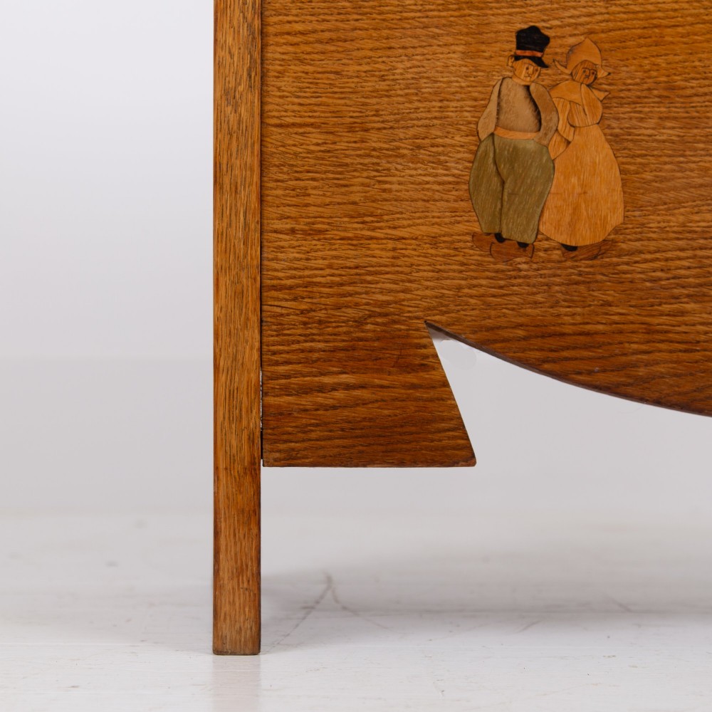 An Arts and Crafts solid oak box settle featuring heart cut-out side panels, an arched backrest, and figural wood inlay on the front apron. View V