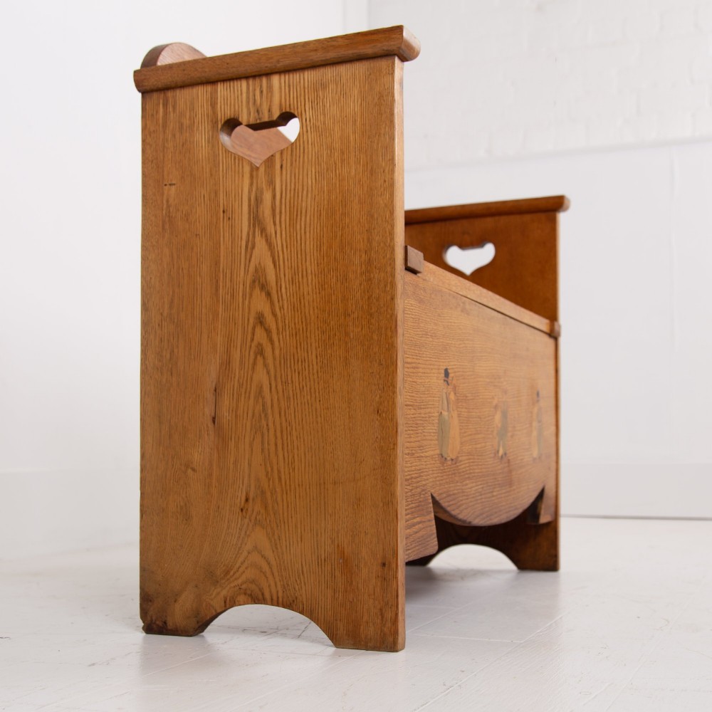 An Arts and Crafts solid oak box settle featuring heart cut-out side panels, an arched backrest, and figural wood inlay on the front apron. View VII