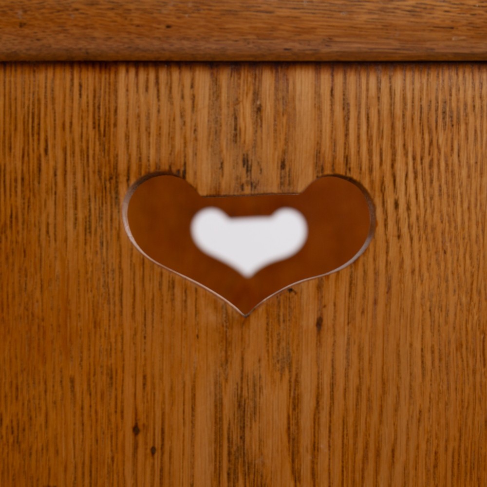 An Arts and Crafts solid oak box settle featuring heart cut-out side panels, an arched backrest, and figural wood inlay on the front apron. View VIII