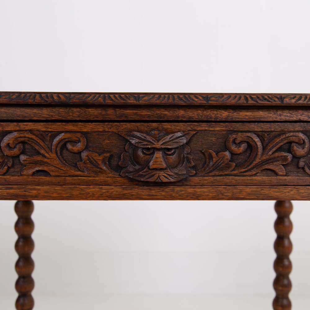 A dark oak Victorian side table featuring a single drawer carved with a Green Man mask motif, bobbin-turned legs, and a lower rectangular stretcher. View III