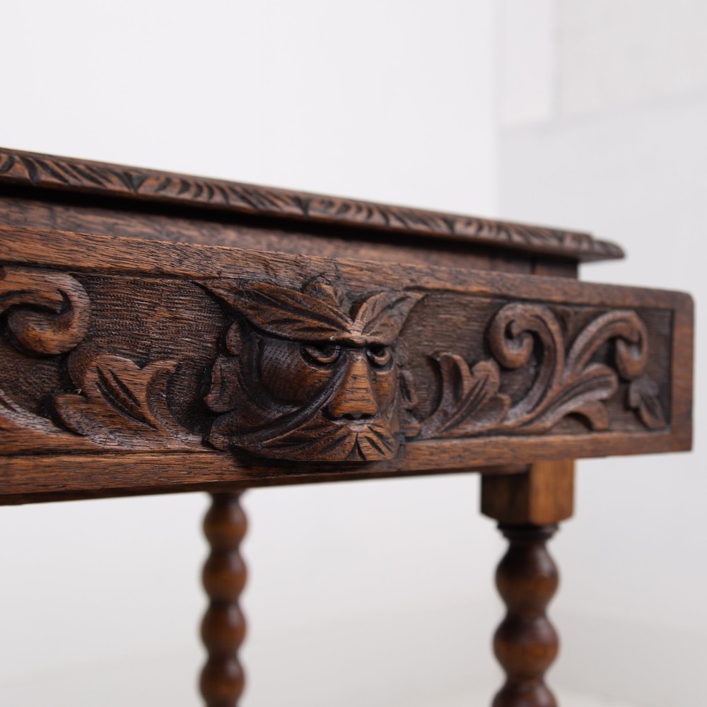 A dark oak Victorian side table featuring a single drawer carved with a Green Man mask motif, bobbin-turned legs, and a lower rectangular stretcher. View IV