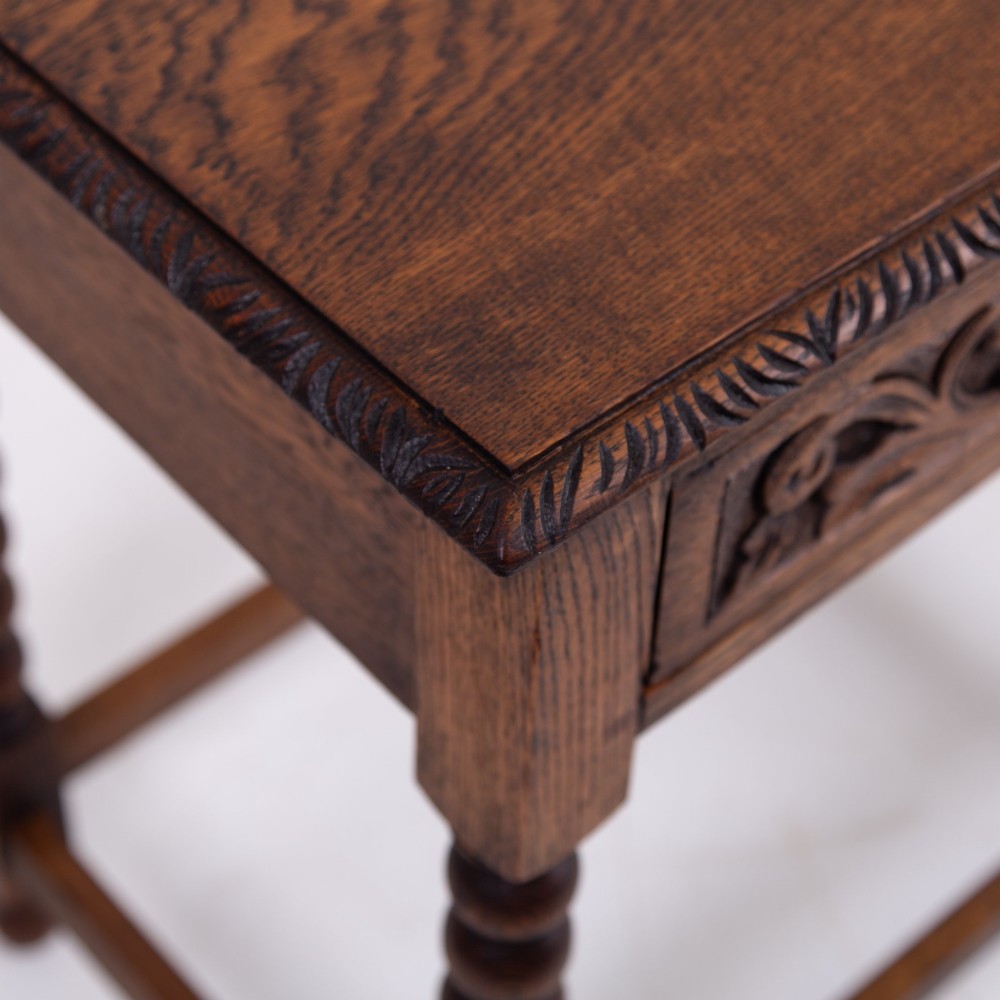 A dark oak Victorian side table featuring a single drawer carved with a Green Man mask motif, bobbin-turned legs, and a lower rectangular stretcher. View V