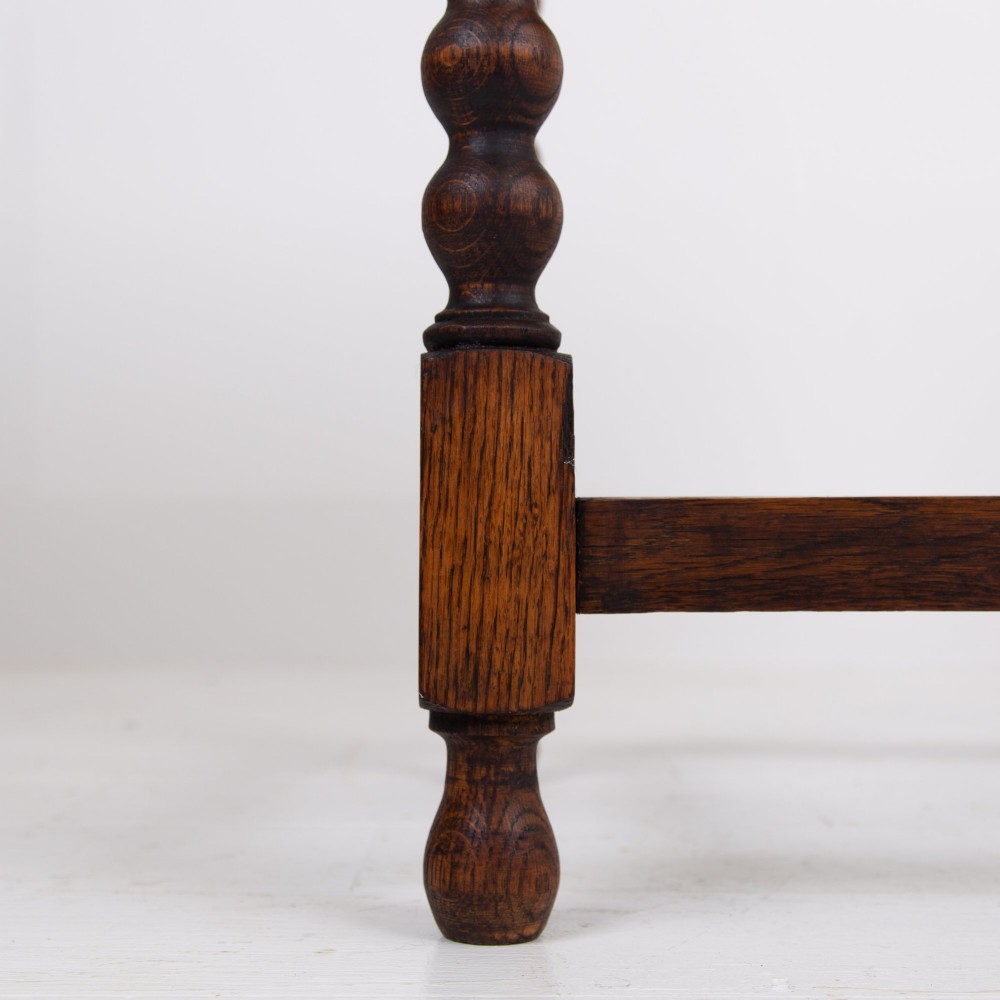 A dark oak Victorian side table featuring a single drawer carved with a Green Man mask motif, bobbin-turned legs, and a lower rectangular stretcher. View VI