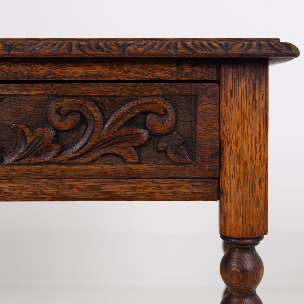 A dark oak Victorian side table featuring a single drawer carved with a Green Man mask motif, bobbin-turned legs, and a lower rectangular stretcher. View VII