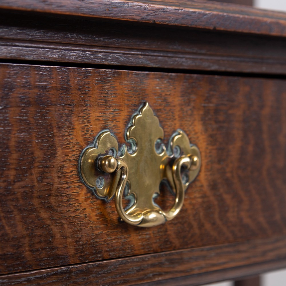 A dark oak console hall table featuring a carved back gallery, two drawers with brass backplate handles, and turned front legs. View IV