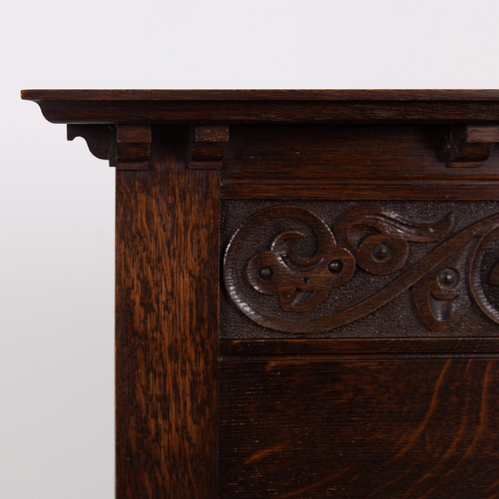 A dark oak console hall table featuring a carved back gallery, two drawers with brass backplate handles, and turned front legs. View VII