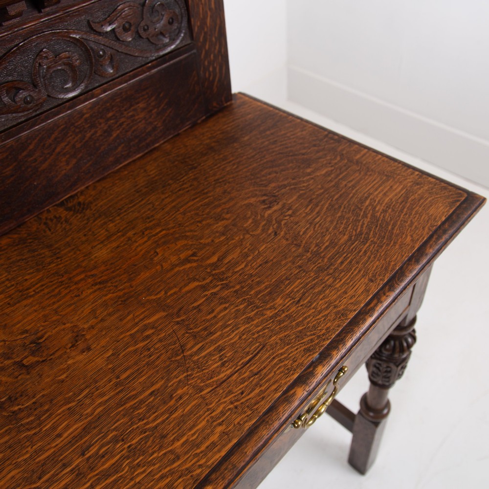 A dark oak console hall table featuring a carved back gallery, two drawers with brass backplate handles, and turned front legs. View XI