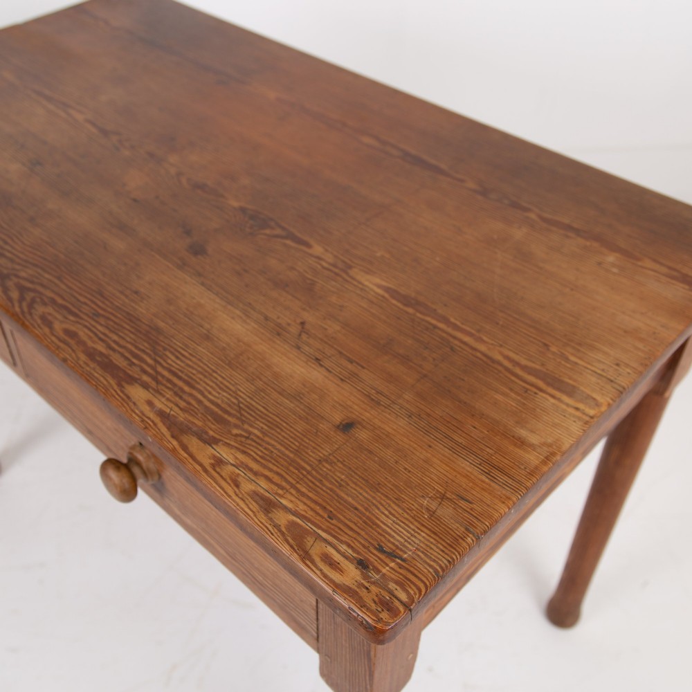 An early 20th-century pitch pine writing desk with two front drawers, wooden turned knobs, and four turned legs. View VI
