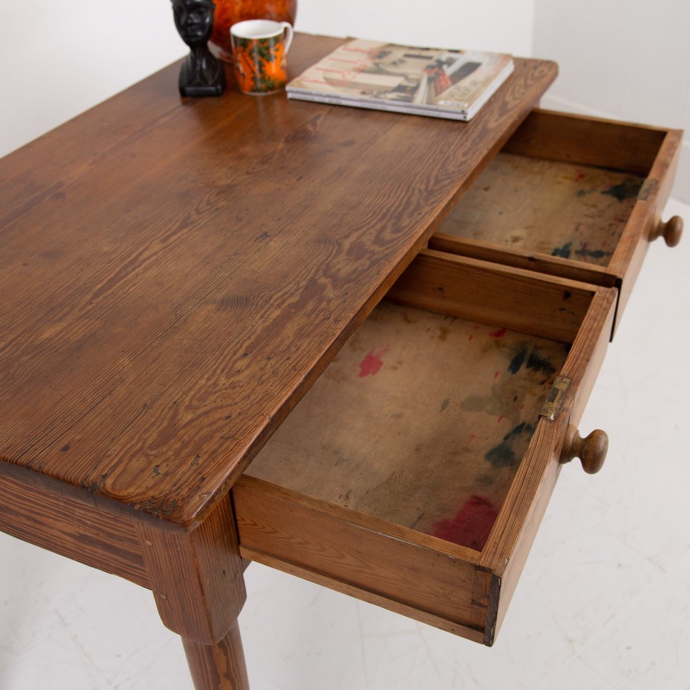 An early 20th-century pitch pine writing desk with two front drawers, wooden turned knobs, and four turned legs. View X