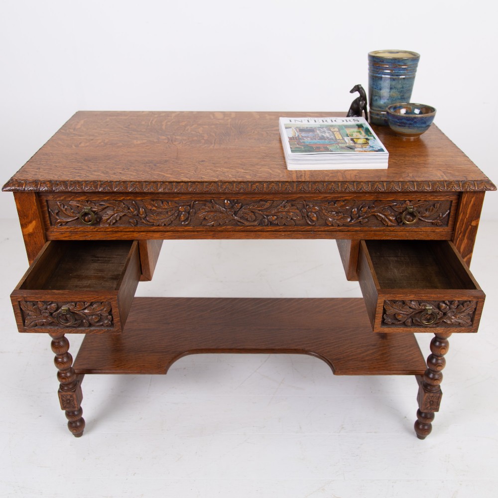 An oak writing desk featuring three carved foliage drawer fronts, bobbin-turned legs, brass drop handles, and a low under-tier shelf. View IV