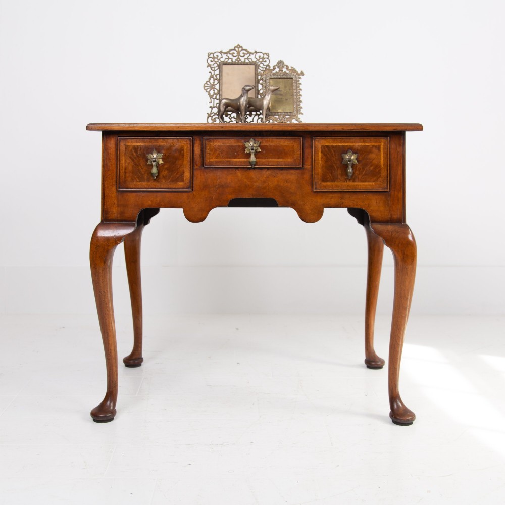 An antique warm brown walnut lowboy table featuring three drawers with brass handles, a shaped apron, and four cabriole legs ending in pad feet. View II