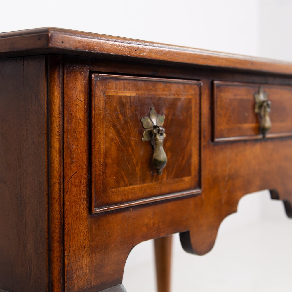 An antique warm brown walnut lowboy table featuring three drawers with brass handles, a shaped apron, and four cabriole legs ending in pad feet. View III