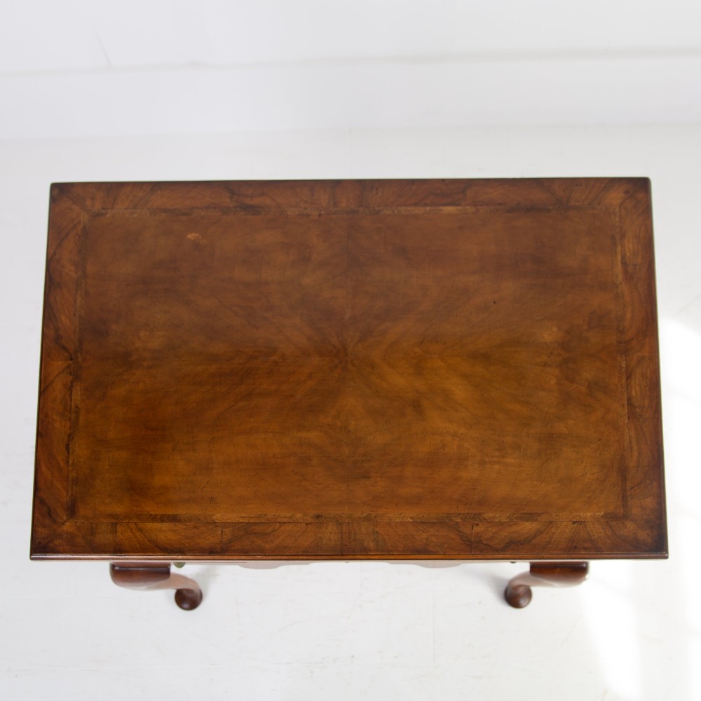 An antique warm brown walnut lowboy table featuring three drawers with brass handles, a shaped apron, and four cabriole legs ending in pad feet. View VII