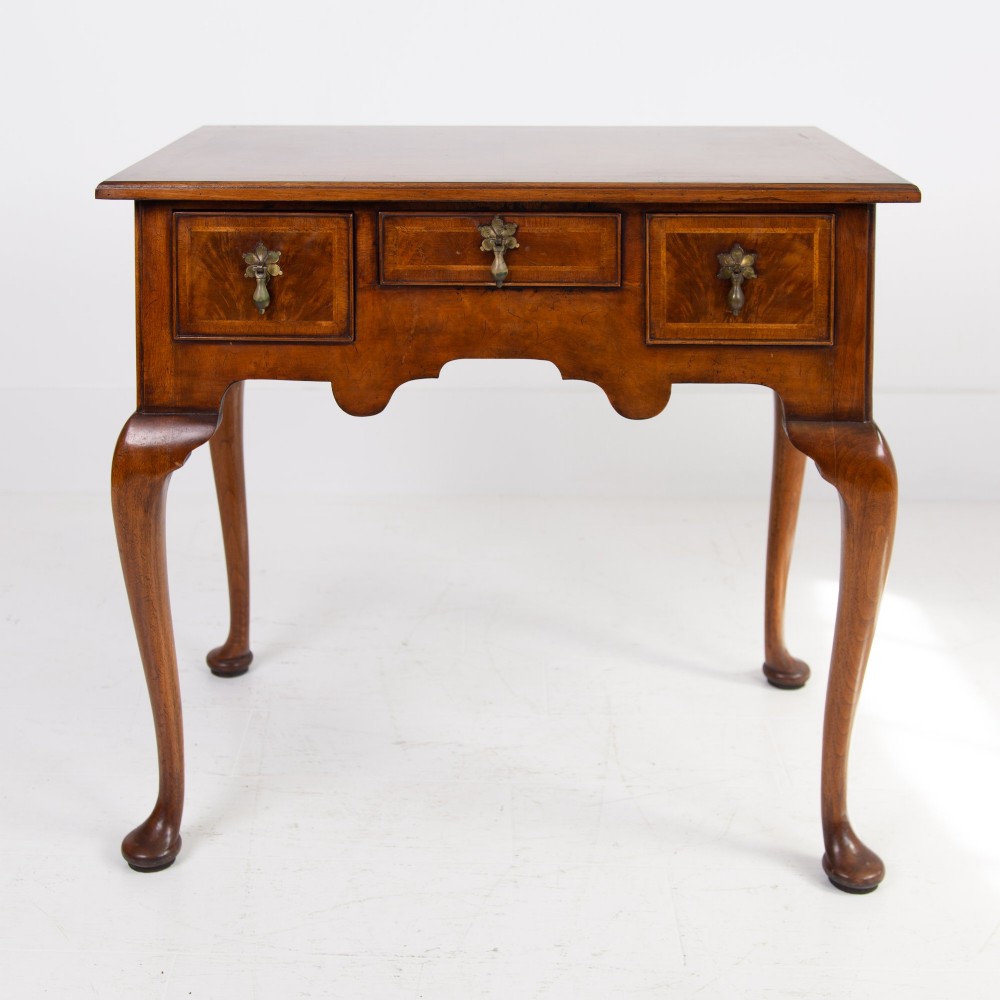 An antique warm brown walnut lowboy table featuring three drawers with brass handles, a shaped apron, and four cabriole legs ending in pad feet. View VIII