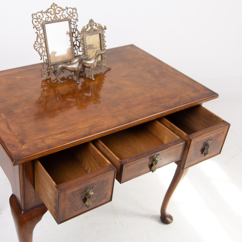 An antique warm brown walnut lowboy table featuring three drawers with brass handles, a shaped apron, and four cabriole legs ending in pad feet. View IX