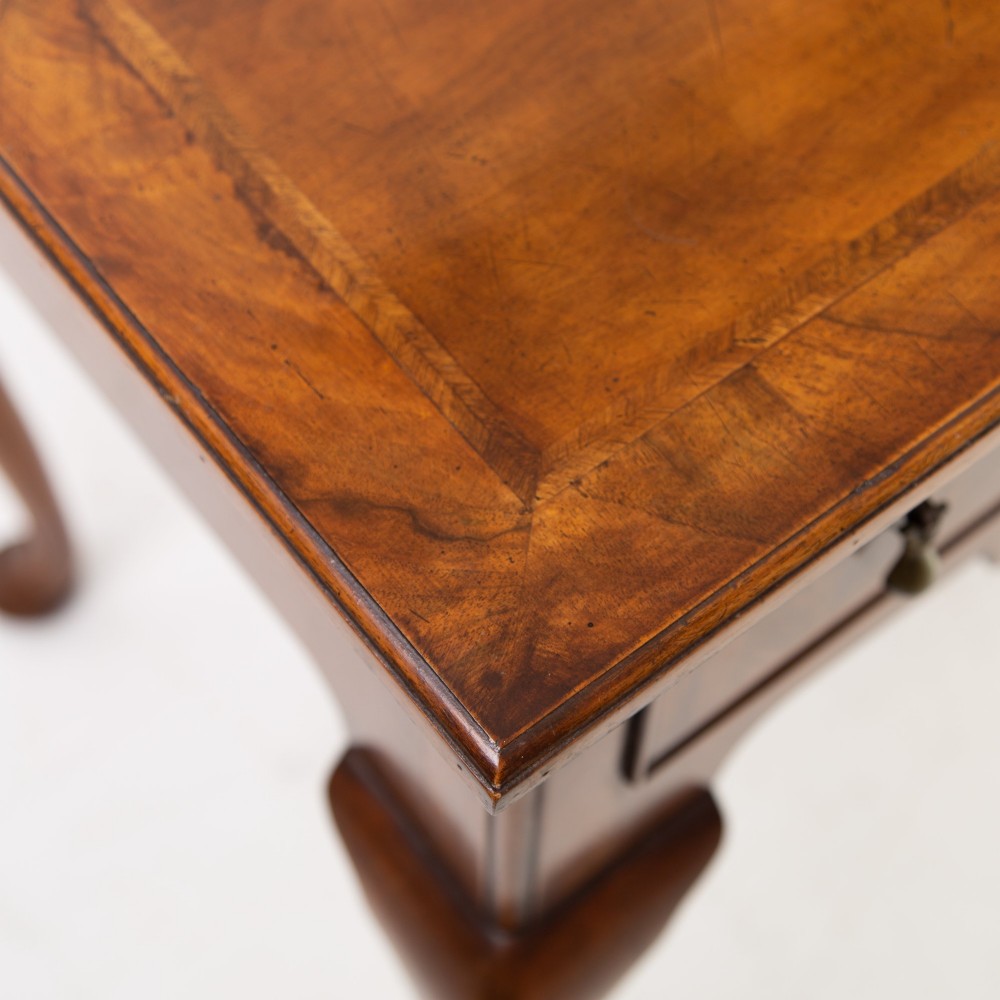 An antique warm brown walnut lowboy table featuring three drawers with brass handles, a shaped apron, and four cabriole legs ending in pad feet. View X