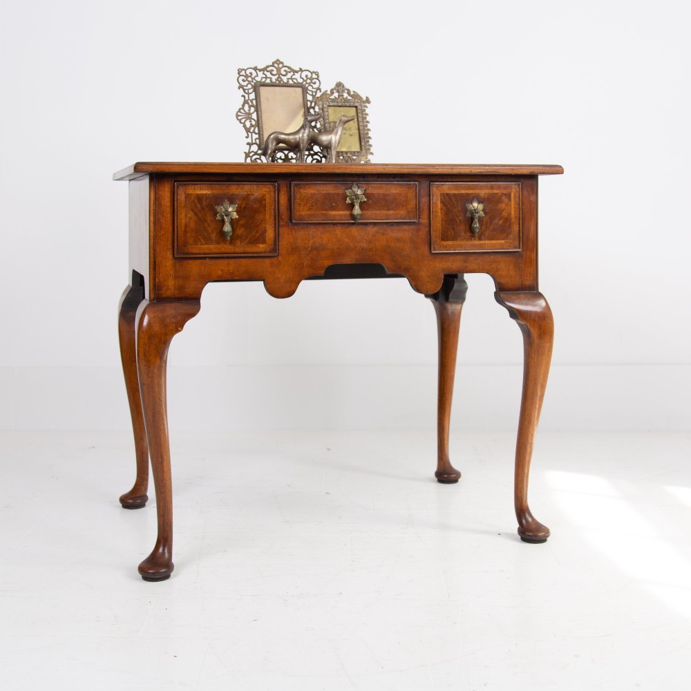 An antique warm brown walnut lowboy table featuring three drawers with brass handles, a shaped apron, and four cabriole legs ending in pad feet. View XII