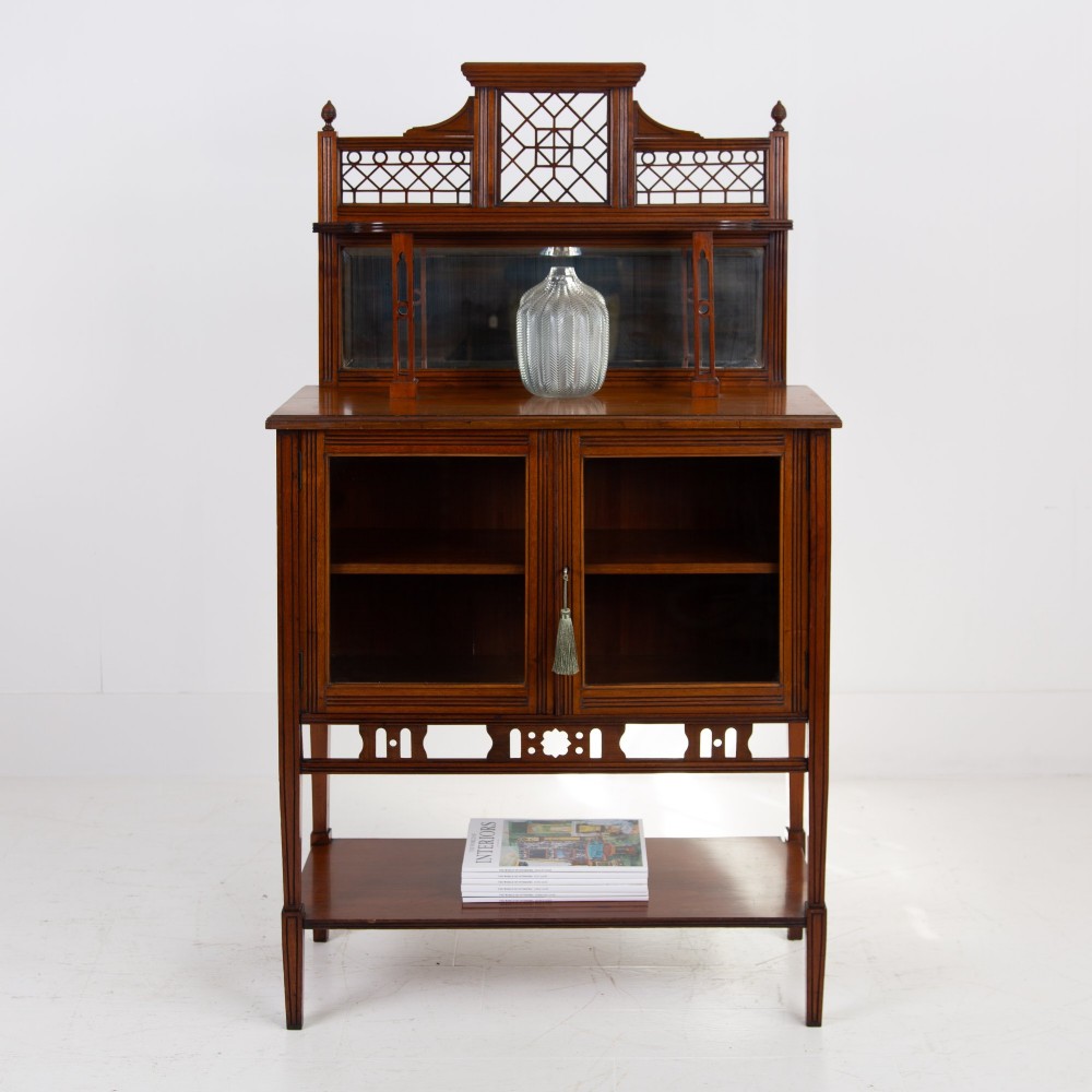 An Aesthetic Movement dark mahogany glazed cabinet with an intricate fretwork upper superstructure, mirrored back, twin glass doors, and a open lower shelf. View II