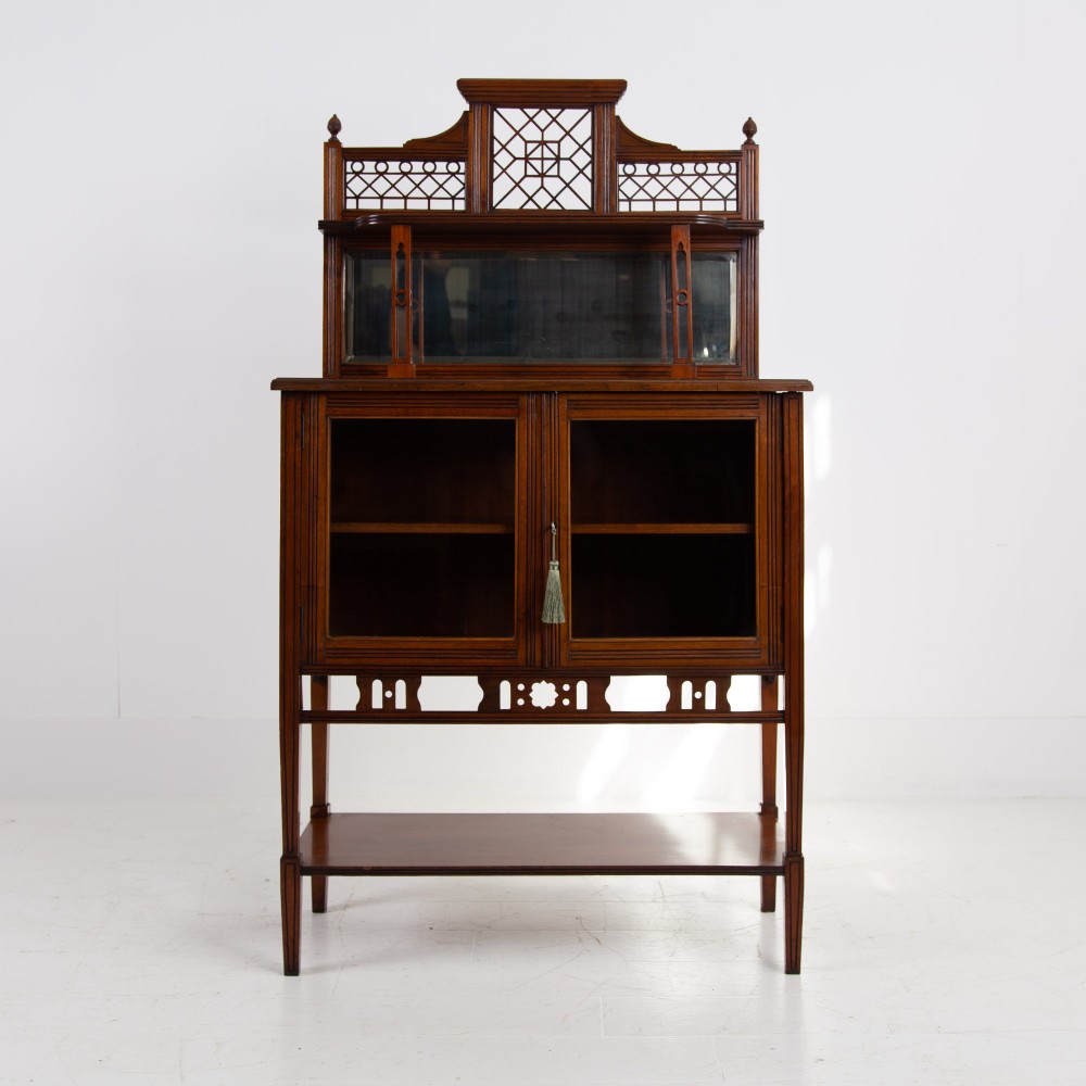 An Aesthetic Movement dark mahogany glazed cabinet with an intricate fretwork upper superstructure, mirrored back, twin glass doors, and a open lower shelf. View IV
