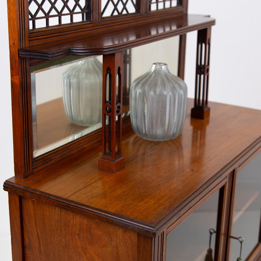An Aesthetic Movement dark mahogany glazed cabinet with an intricate fretwork upper superstructure, mirrored back, twin glass doors, and a open lower shelf. View V