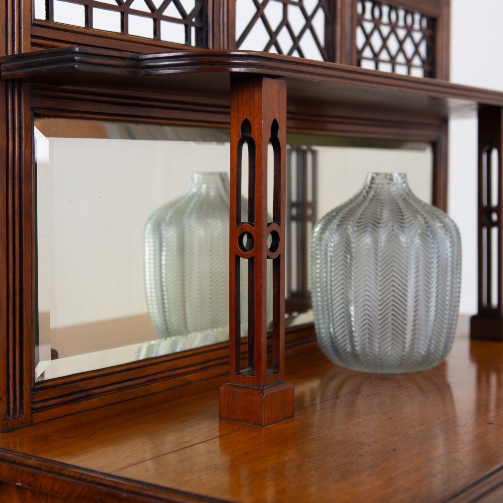 An Aesthetic Movement dark mahogany glazed cabinet with an intricate fretwork upper superstructure, mirrored back, twin glass doors, and a open lower shelf. View VI