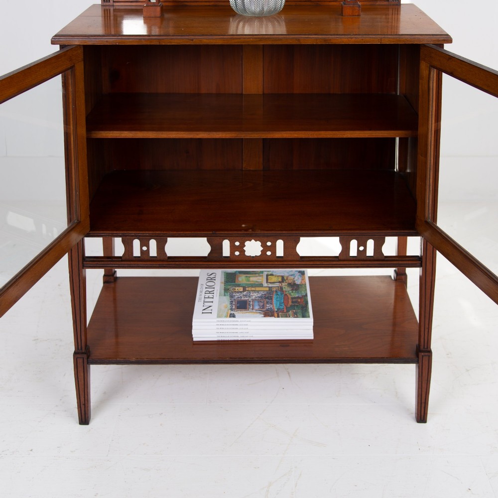 An Aesthetic Movement dark mahogany glazed cabinet with an intricate fretwork upper superstructure, mirrored back, twin glass doors, and a open lower shelf. View VIII