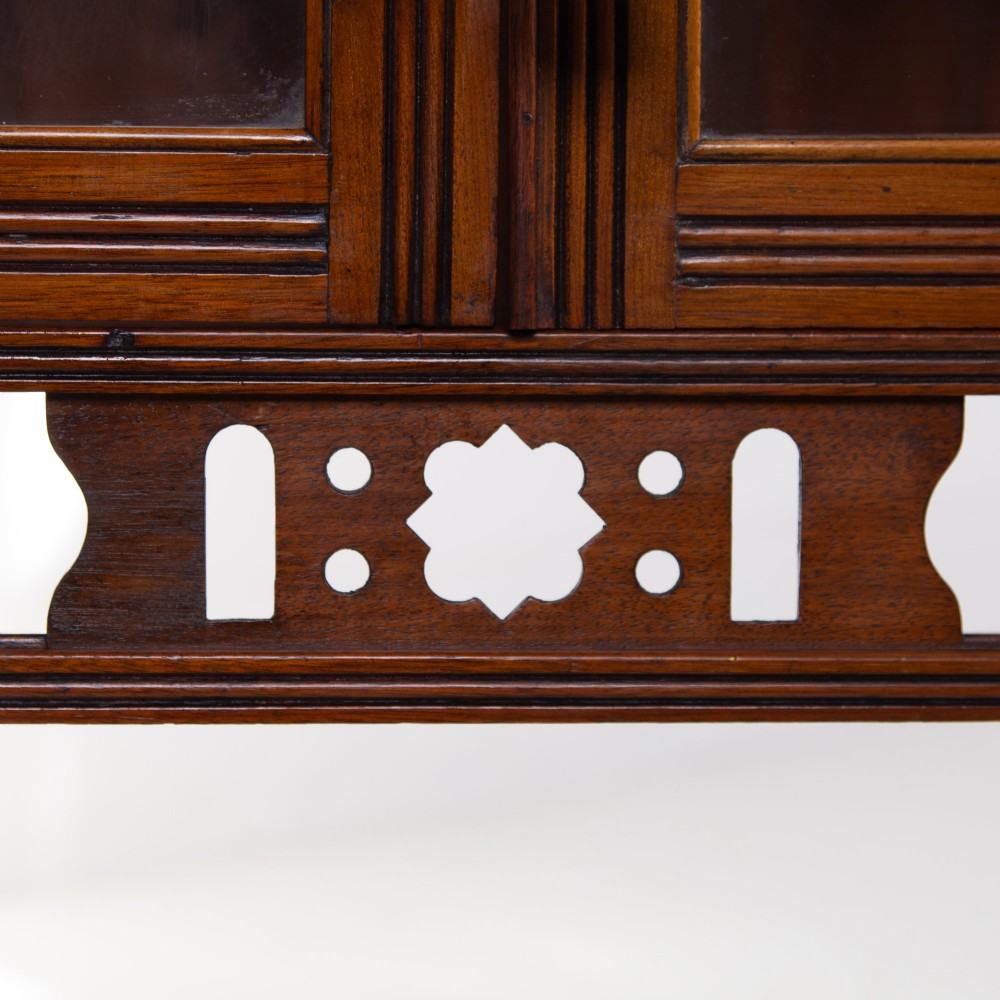 An Aesthetic Movement dark mahogany glazed cabinet with an intricate fretwork upper superstructure, mirrored back, twin glass doors, and a open lower shelf. View IX