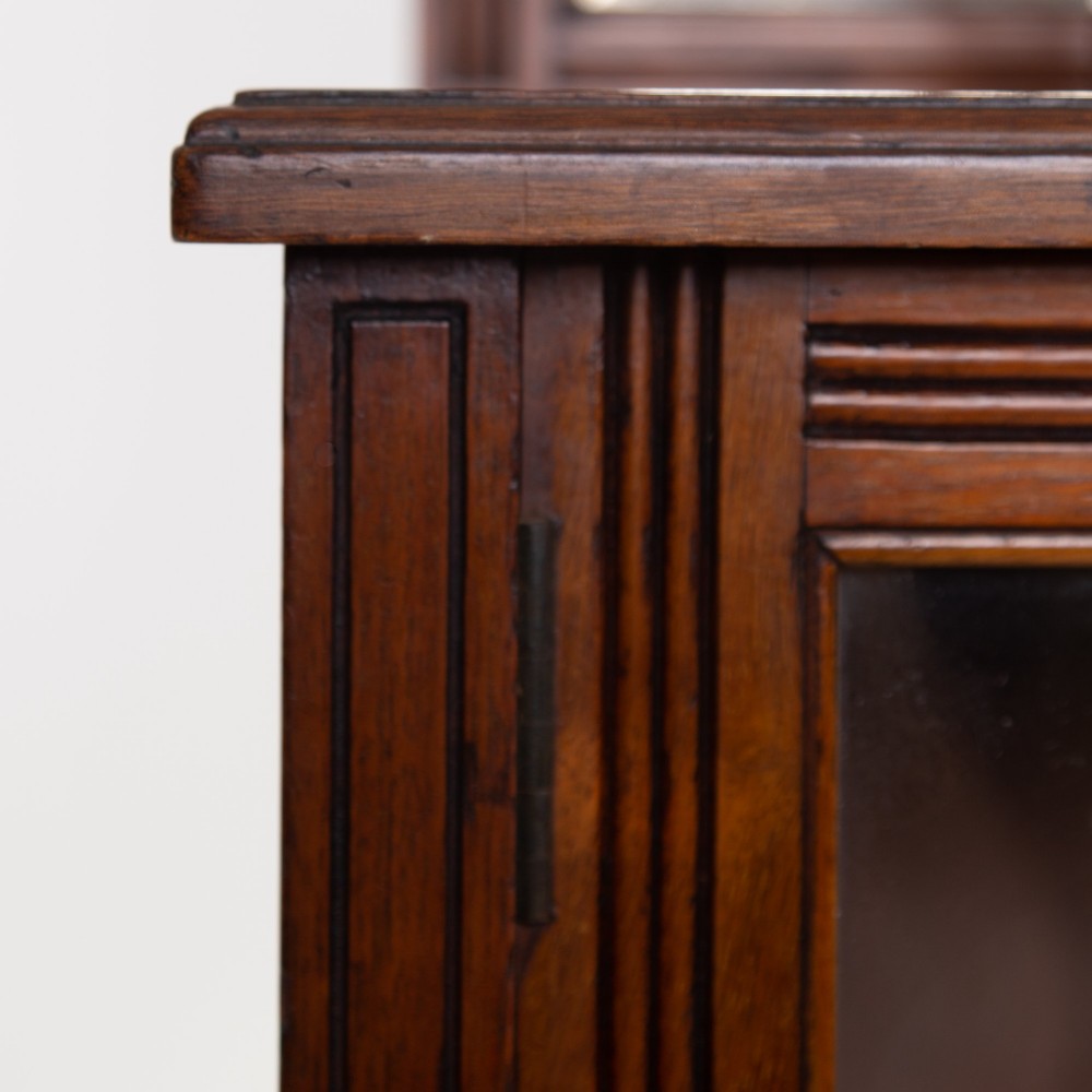 An Aesthetic Movement dark mahogany glazed cabinet with an intricate fretwork upper superstructure, mirrored back, twin glass doors, and a open lower shelf. View XI