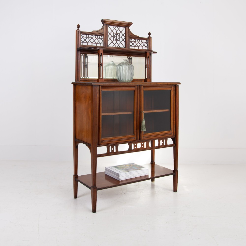 An Aesthetic Movement dark mahogany glazed cabinet with an intricate fretwork upper superstructure, mirrored back, twin glass doors, and a open lower shelf. View XIII