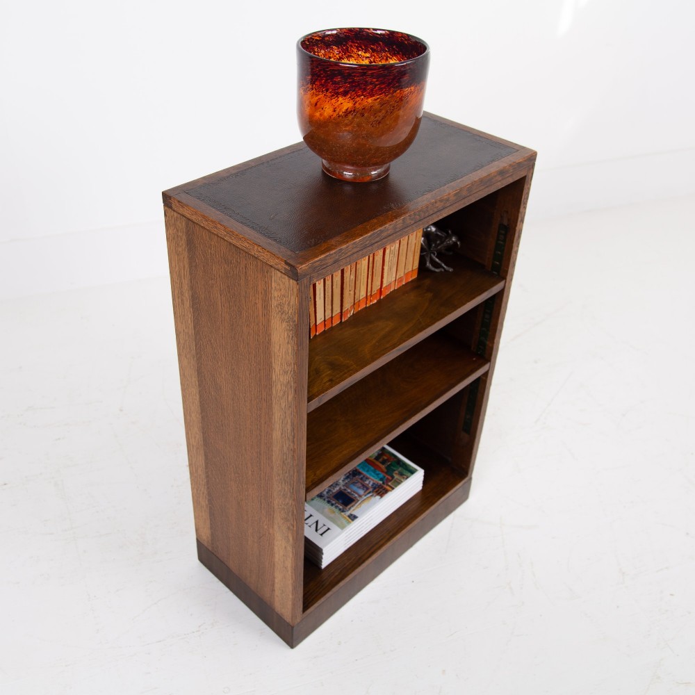 A 1930s dark oak open bookcase featuring two adjustable shelves, a leather-inset top surface, and a solid plinth base. View II