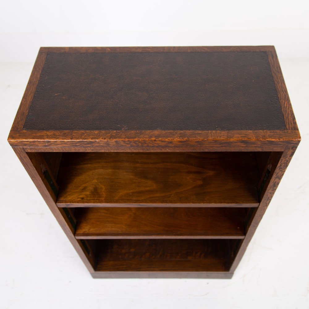 A 1930s dark oak open bookcase featuring two adjustable shelves, a leather-inset top surface, and a solid plinth base. View IV