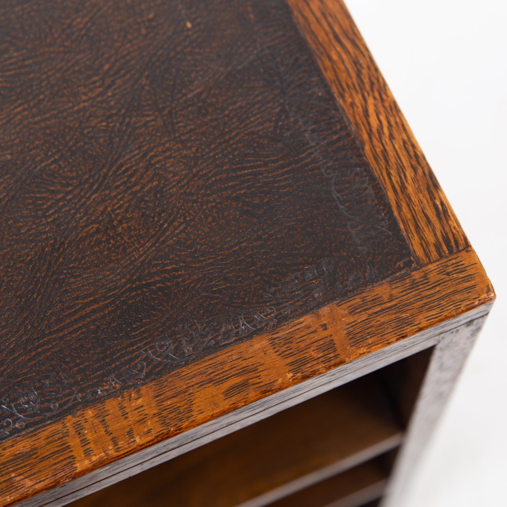 A 1930s dark oak open bookcase featuring two adjustable shelves, a leather-inset top surface, and a solid plinth base. View V