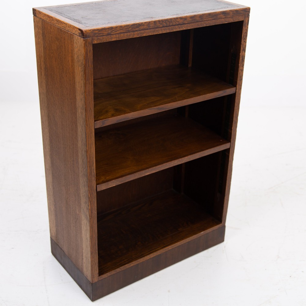 A 1930s dark oak open bookcase featuring two adjustable shelves, a leather-inset top surface, and a solid plinth base. View VII