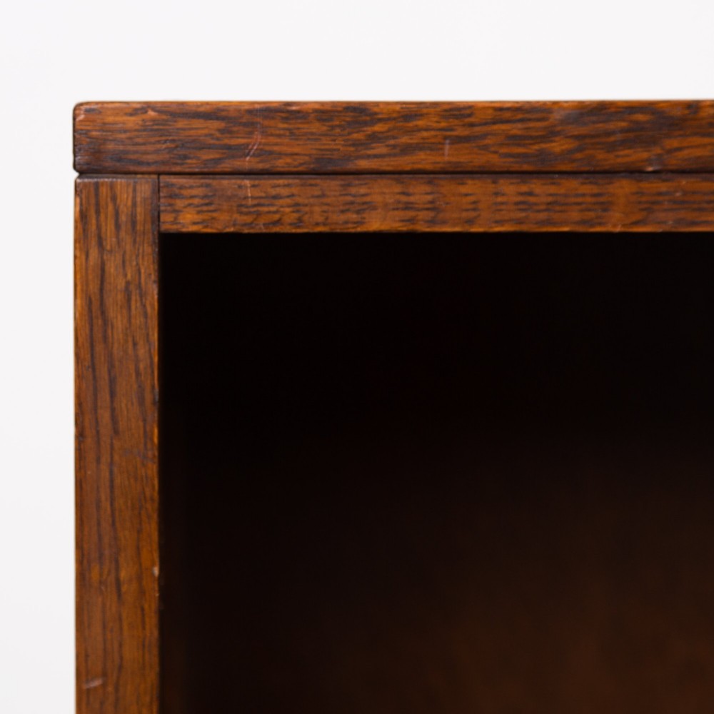 A 1930s dark oak open bookcase featuring two adjustable shelves, a leather-inset top surface, and a solid plinth base. View IX
