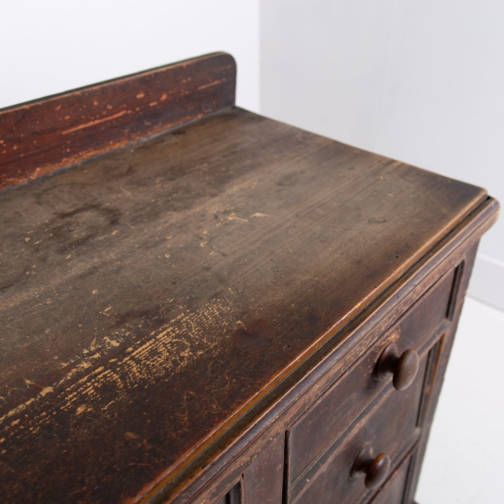 A 19th-century dark brown painted wooden kitchen dresser with seven drawers, a central cupboard, wooden knobs, and turned feet. View XII