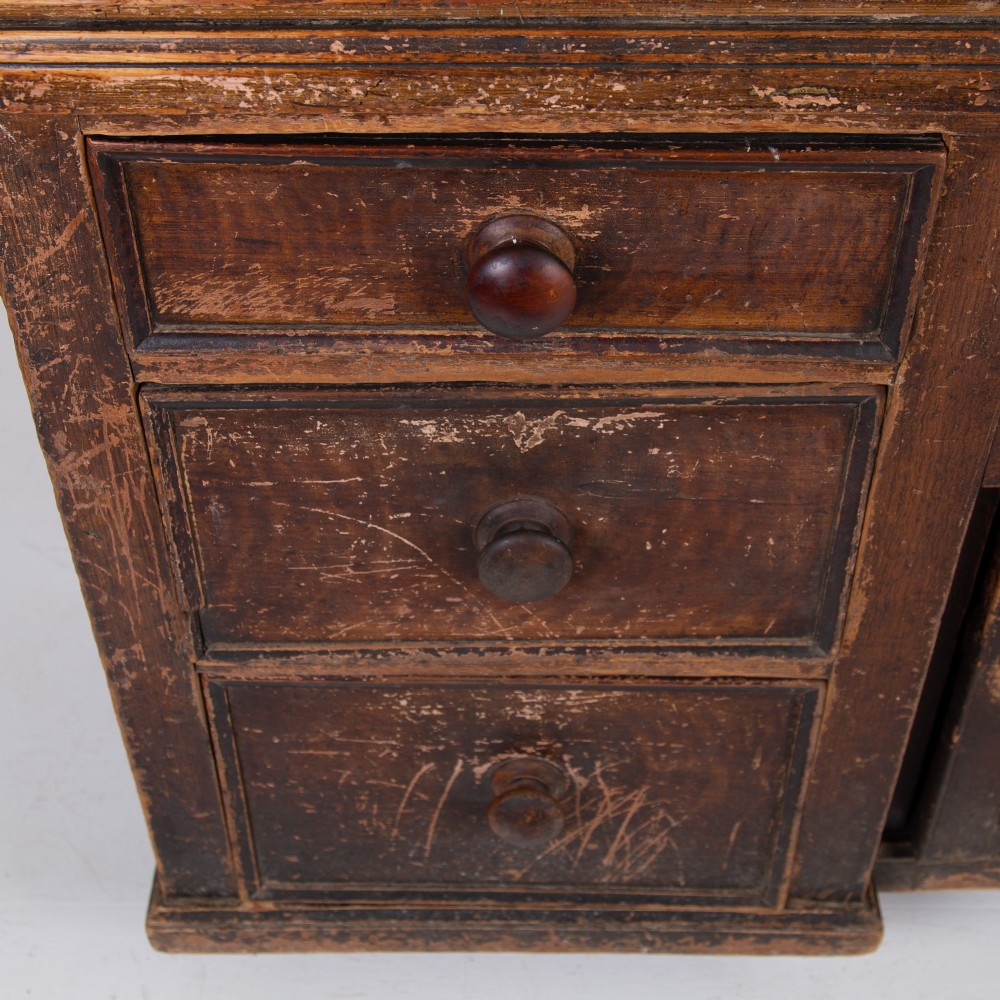 A 19th-century dark brown painted wooden kitchen dresser with seven drawers, a central cupboard, wooden knobs, and turned feet. View XIII