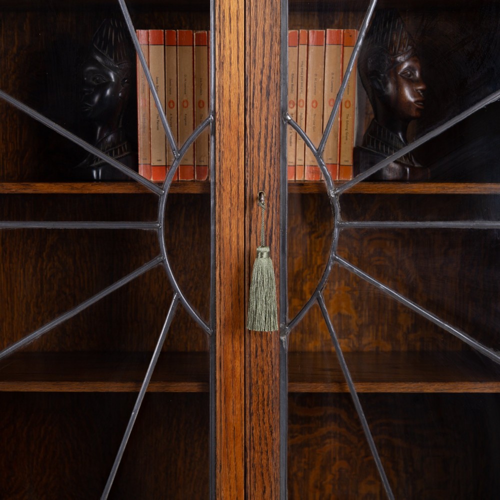 An Art Deco oak cabinet featuring two upper leaded glass doors with a geometric motif and a lower two-door wooden cupboard on stepped feet. View III