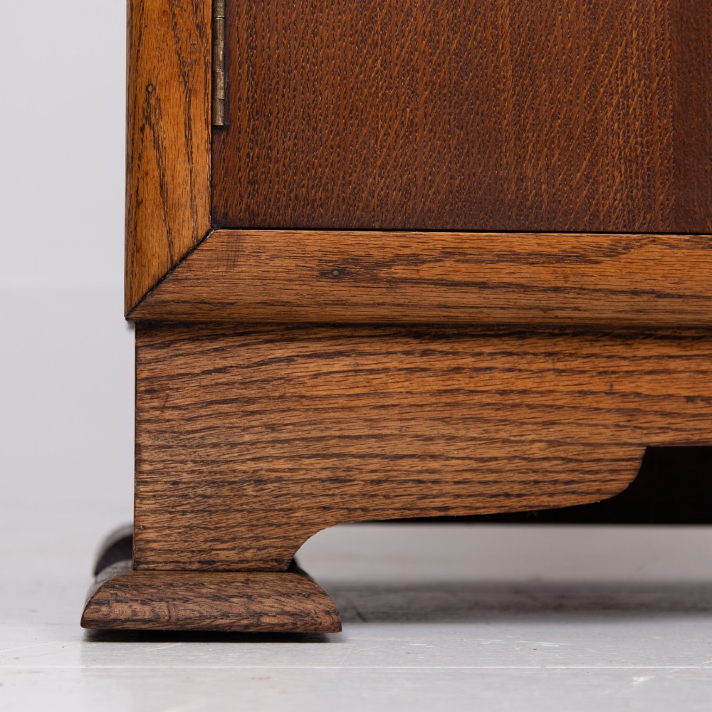 An Art Deco oak cabinet featuring two upper leaded glass doors with a geometric motif and a lower two-door wooden cupboard on stepped feet. View VIII
