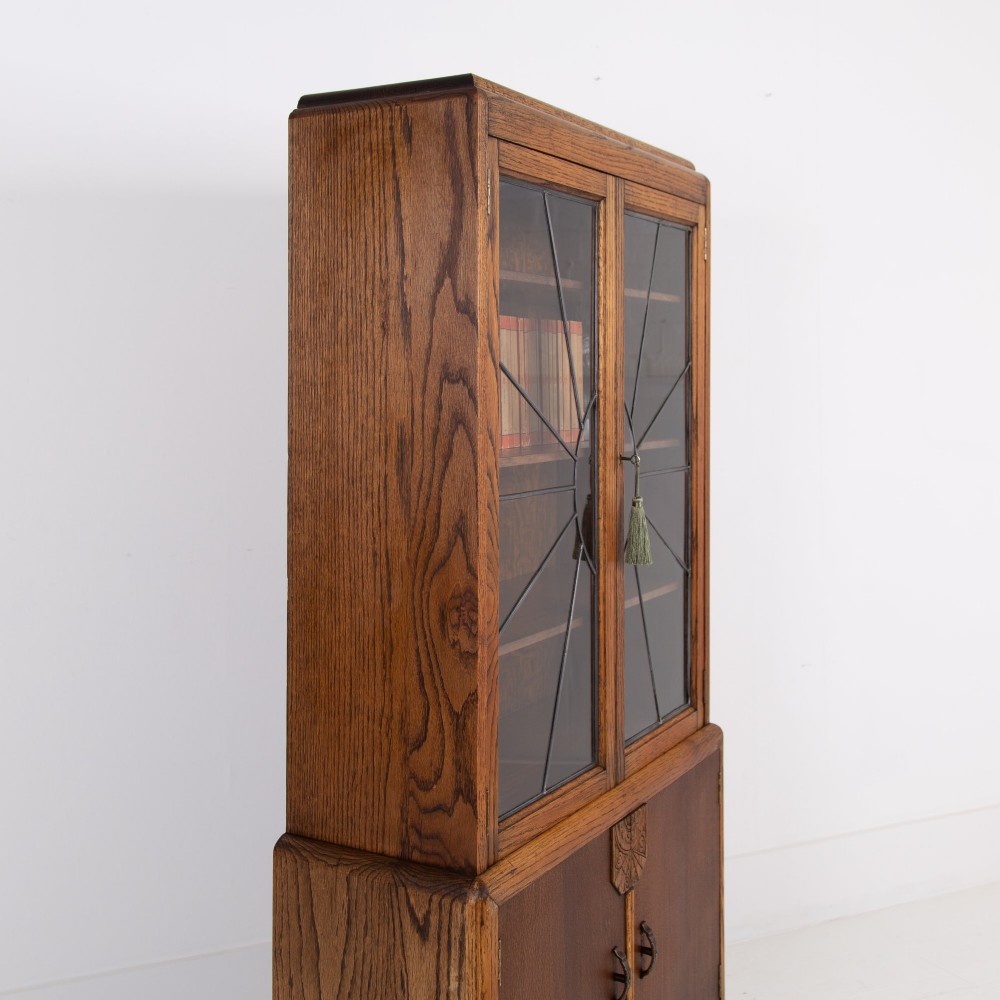 An Art Deco oak cabinet featuring two upper leaded glass doors with a geometric motif and a lower two-door wooden cupboard on stepped feet. View XII