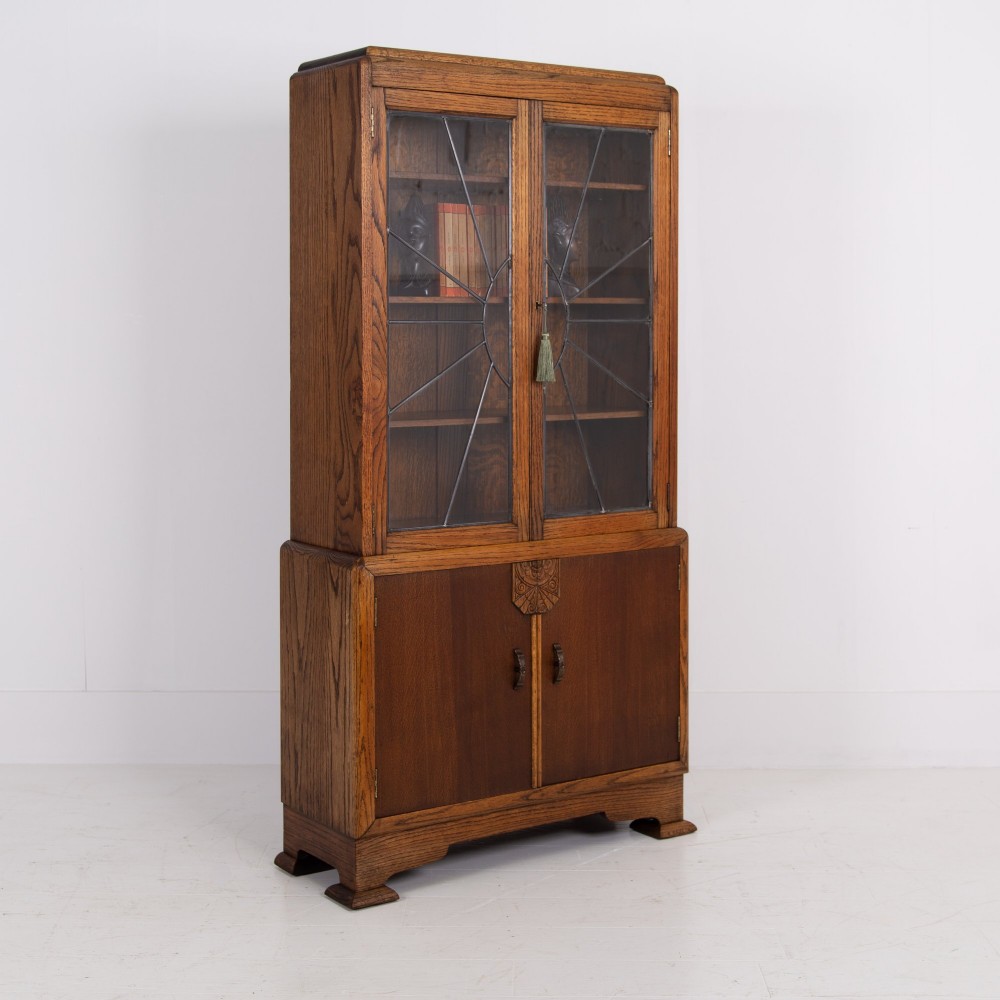 An Art Deco oak cabinet featuring two upper leaded glass doors with a geometric motif and a lower two-door wooden cupboard on stepped feet. View XIV