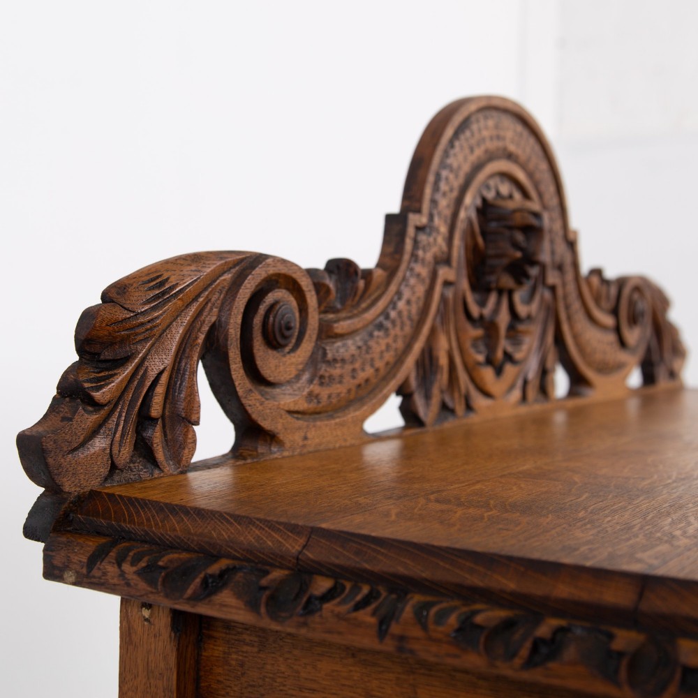 An ornate carved oak console table with a decorative mask crest upstand, an intricate interlace apron design, and carved turned legs. View IV
