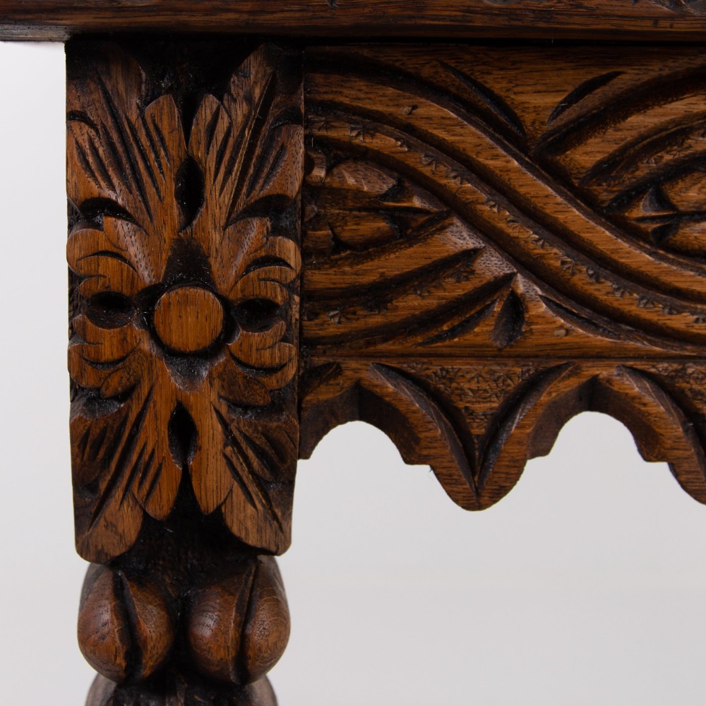 An ornate carved oak console table with a decorative mask crest upstand, an intricate interlace apron design, and carved turned legs. View VI