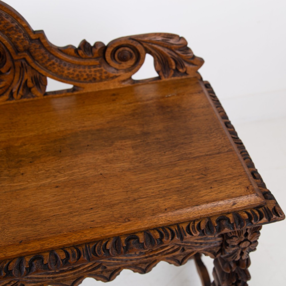 An ornate carved oak console table with a decorative mask crest upstand, an intricate interlace apron design, and carved turned legs. View X