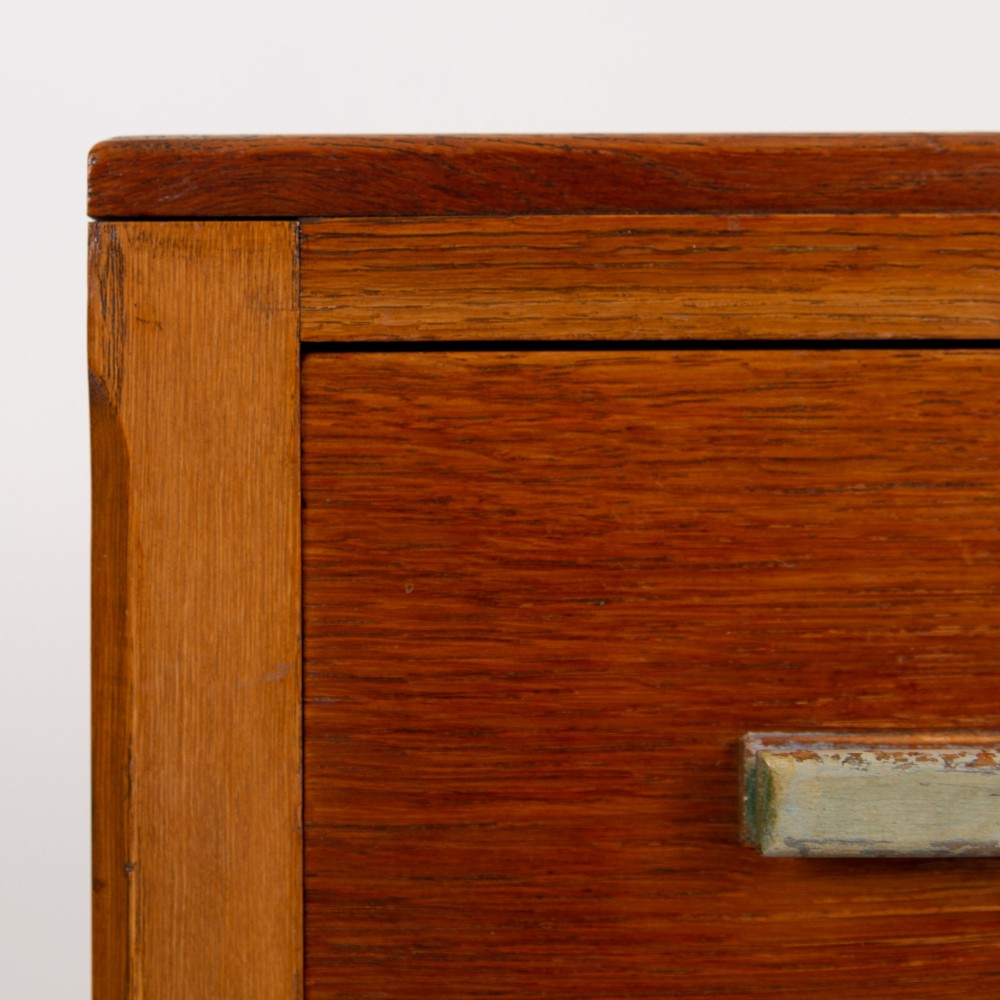 An Art Deco medium oak cabinet featuring two upper drawers, a lower cupboard door, and rectangular metal pulls on a plinth base. View V