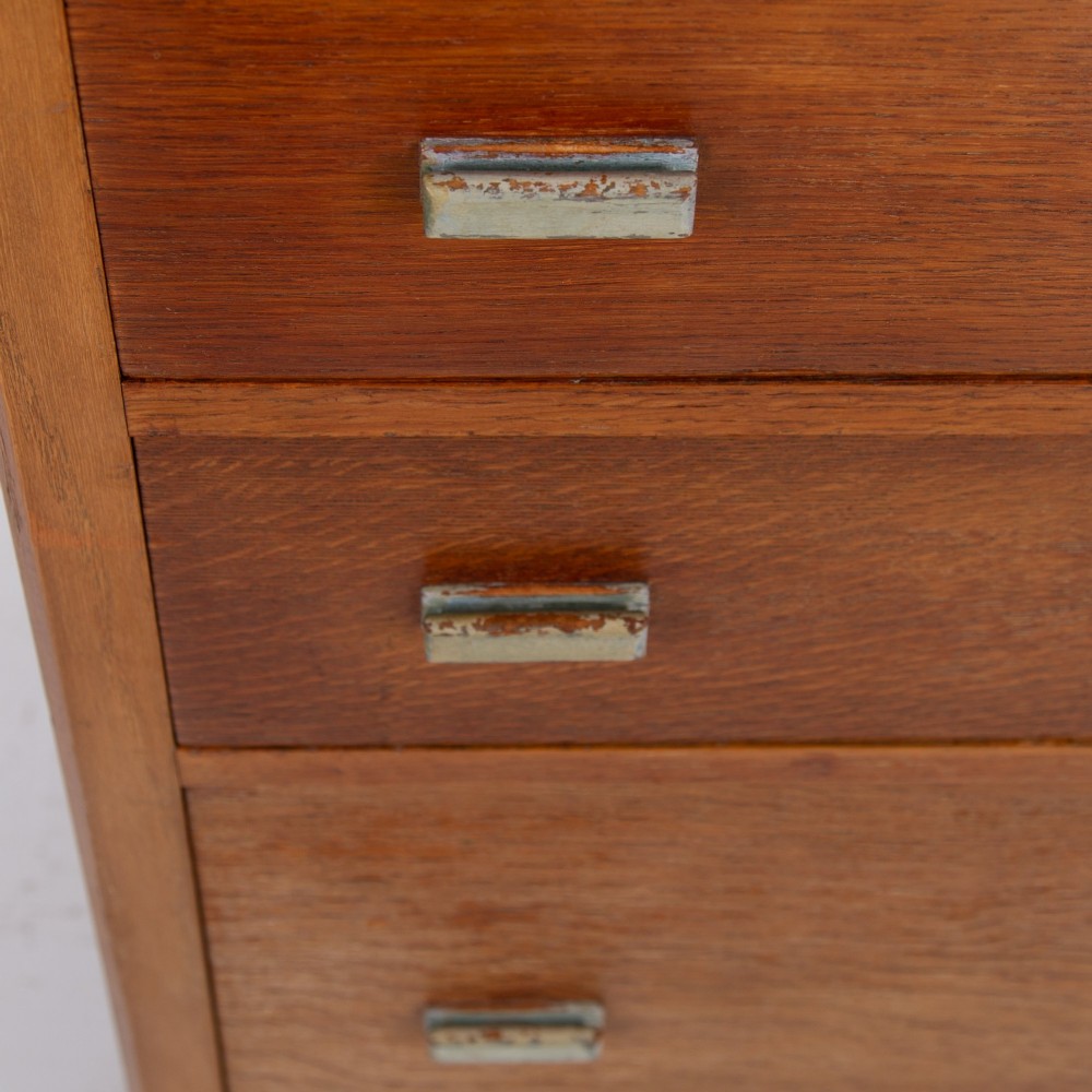 An Art Deco medium oak cabinet featuring two upper drawers, a lower cupboard door, and rectangular metal pulls on a plinth base. View VI
