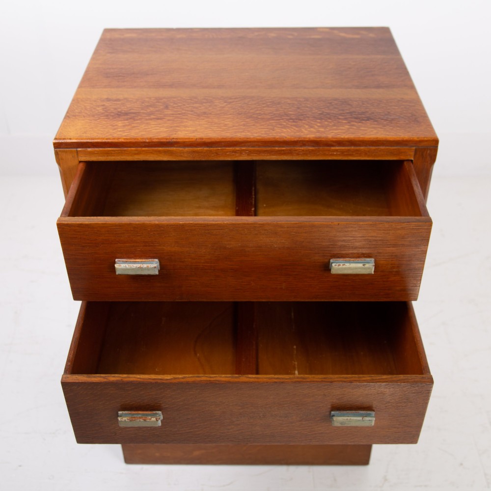 An Art Deco medium oak cabinet featuring two upper drawers, a lower cupboard door, and rectangular metal pulls on a plinth base. View XII