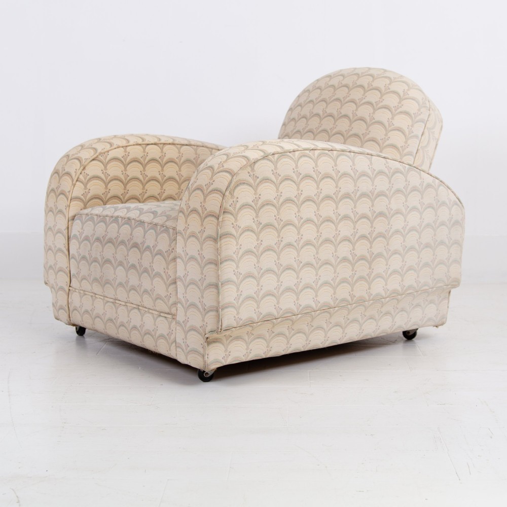 A pair of 1930s Art Deco upholstered armchairs featuring rounded arms, a scalloped fabric pattern, and small integrated casters. View II