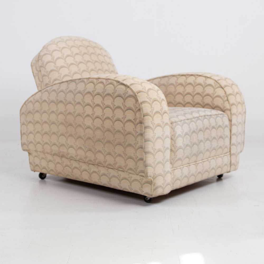 A pair of 1930s Art Deco upholstered armchairs featuring rounded arms, a scalloped fabric pattern, and small integrated casters. View VI