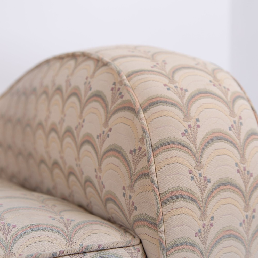A pair of 1930s Art Deco upholstered armchairs featuring rounded arms, a scalloped fabric pattern, and small integrated casters. View VIII